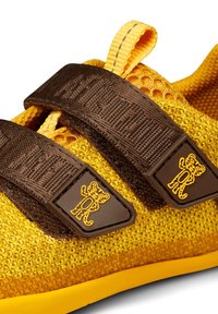 Baskets en maille jaune avec deux bandes Velcro marron foncé, chacune avec un petit logo tigre cartoon jaune.