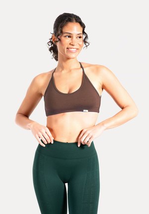 Reggiseno sportivo atletico marrone con spalline larghe e scollo a U, abbinato a leggings verde scuro a vita alta con un motivo sottile.