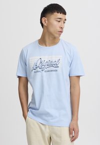 Lys blå bomulls T-skjorte med rund hals, med grafisk trykk "Original Global Jeansmaker" i mørk blå og hvite detaljer.