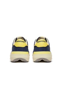 Un paio di sneaker Saucony blu navy e gialle viste da dietro, con spesse suole beige e logo sulle linguette gialle del tallone.