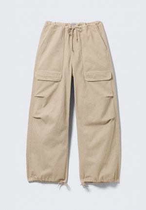 Beige Cargohosen mit weitem Bein, Kordelzugbund und -säumen, Klappentaschen an den Oberschenkeln und Seitentaschen mit Schlitz.