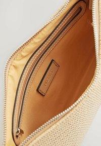 Beige vävd clutchväska med en slät insida, utrustad med en dragkedjeficka och en liten läderetikett präglad med "NEXT."