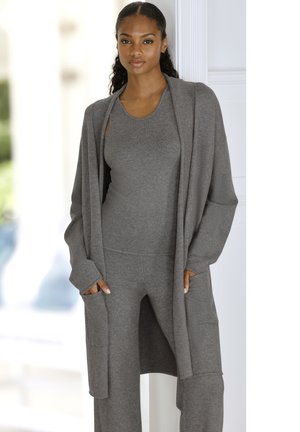 Grauer Strickcardigan mit offenem Vorderteil, langen Ärmeln und seitlichen Taschen. Trägt man über einem passenden Tanktop und einer Hose, die eine glatte Textur aufweisen.