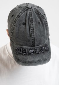 Graue Baumwoll-Baseballmütze mit "WASTED" auf der Vorderseite gestickt, mit sechs Panels und einem gebogenen Schirm. Abgetragene Textur mit sichtbaren Nähten.