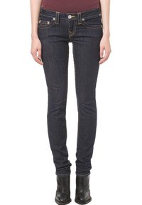 Mörkblå slim-fit jeans i denim, med framfickor, subtila sömnadsdetaljer och en figurnära design. Bärs med svarta ankelstövlar.