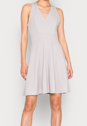 Robe sans manches gris pâle jusqu'au genou avec col en V et taille cintrée, portée par une personne debout sur un fond uni.