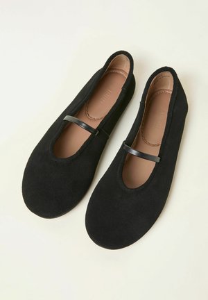 Fekete velúr balettcipő kerek orral és bőr pánttal a talp fölött, sima belső béléssel és lapos talppal.