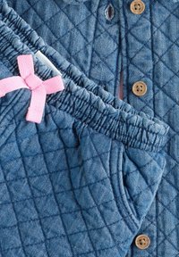 Gequilte denim loungewear set in donkerblauw met roze strikaccent. Kenmerkt knopen en een elastische tailleband met geplooide textuur.