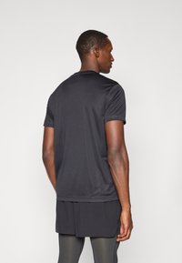 Černé sportovní tričko s krátkým rukávem vyrobené z hladké, lehké tkaniny. Má klasický výstřih a jednoduchý design, bez viditelných log.