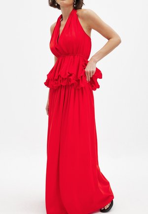 Rød halterneck kjole med en flagrende peplum detalje ved taljen. Den er lavet af glat stof og har en svajende, maxilængde nederdel.