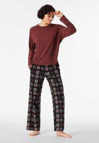 Long-sleeve maroon top paired with black pajama pants featuring a geometric pattern in red and cream, made from soft, breathable fabric.