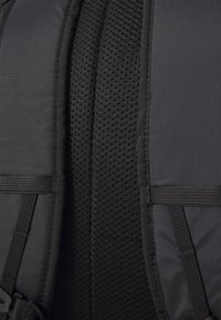Schwarzer Rucksack mit gepolsterten Trägern, die über atmungsaktive Mesh-Abschnitte verfügen. Die Textur ist glatt, mit verstärkten Nähten und verstellbaren Riemen.