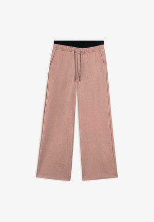 Pantaloni a gamba larga rosa chiaro con vita elasticizzata nera, cordoncino e tasche laterali. Il tessuto ha una consistenza morbida e liscia.