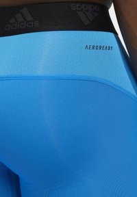 Niebieskie legginsy sportowe z teksturowanym czarnym pasem w talii z logo "adidas" i "AEROREADY". Gładki, dopasowany krój w całej długości.