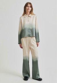 Set di blusa e pantaloni in seta con un motivo ombre che va dal crema al verde, dotato di un colletto classico, vestibilità rilassata e gambe larghe. Texture morbida.