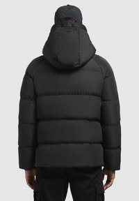 Sort pufferjakke med hætte, der har et quiltet design, glat struktur og elastiske manchetter. Bagviften viser lodrette sømme og et logomærke.