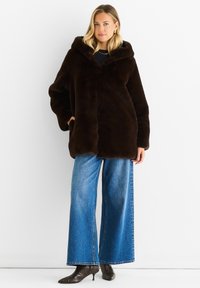 Brown faux fur coat with a hood, featuring a button closure and side pockets; paired with wide-leg blue denim jeans and black heeled boots.