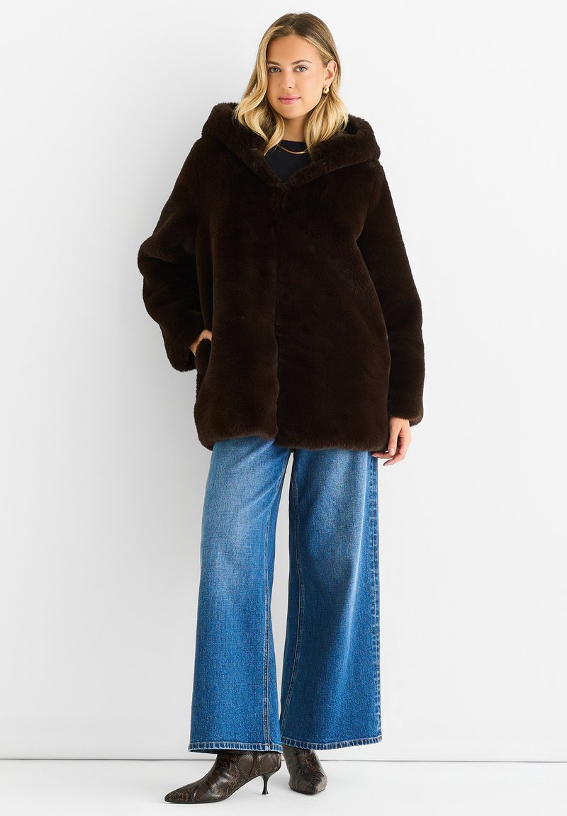 Brown faux fur coat with a hood, featuring a button closure and side pockets; paired with wide-leg blue denim jeans and black heeled boots.
