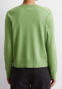 Maglione verde morbido a maglia con collo a giro e orlo e polsini a coste. Texture liscia e design aderente, che mostra un colore uniforme senza motivi.