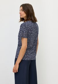 Marineblauw kortemouwenshirt met een bladerenpatroon in lichtblauw. Zachte stof met een getailleerd lijfje en ronde hals. Gepaard met marineblauwe wijde broek.