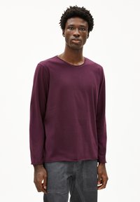 Langsleeve shirt in dieppaars, gemaakt van zachte stof met een ronde hals. Heeft een relaxte pasvorm en een minimalistisch ontwerp.