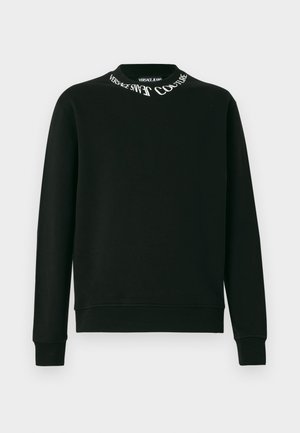 Černá mikina s dlouhým rukávem a kulatým výstřihem, která má bílé nápisy "Versace Jeans Couture" kolem límečku, žebrované manžety a lem.