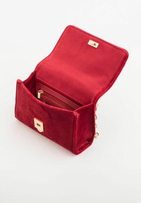 Pochette en velours rouge avec un fermoir doré et une poche zippée à l'intérieur. Le design ouvert permet de voir les détails de son tissu et de ses compartiments.