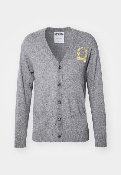 Pelēks kardigans, kas izgatavots no mīksta adīta auduma, ar V-veida kakla izgriezumu, garām piedurknēm, zeltīšu izšūtu emblemu, pogu aizdari un priekšējām kabatām.