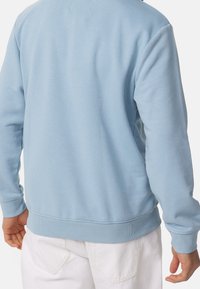 Lichtblauw sweatshirt met een zachte textuur, geribbelde manchetten en een gebreide zoom, met een eenvoudig, onopgesmukt ontwerp aan de achterkant.
