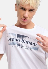Vit bomullströja med grafisk tryck med blå och svarta texter "bruno banani" och "NOT FOR EVERYBODY." Rund hals, avslappnad passform.