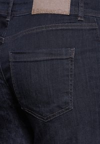 Tmavě modré džíny s jemnou texturou, které mají zadní kapsu a béžovou koženou nášivku na pase označenou "Street One."