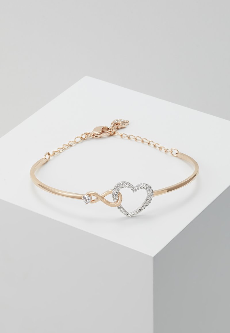 Gold-tone metal bracelet featuring an infinity symbol and heart design, adorned with clear cubic zirconia accents and a lobster clasp closure.