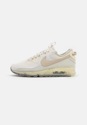 Baskets Nike Air Max beiges avec une tige en mesh, un col rembourré, un amorti en air transparent et une semelle en caoutchouc texturé.