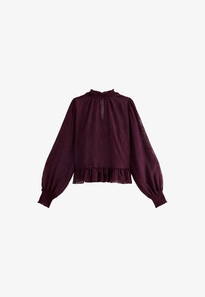 Blouse bordeaux à manches longues, avec un col à volants et un ourlet. Fabriquée en tissu léger avec une finition texturée et des poignets froncés.