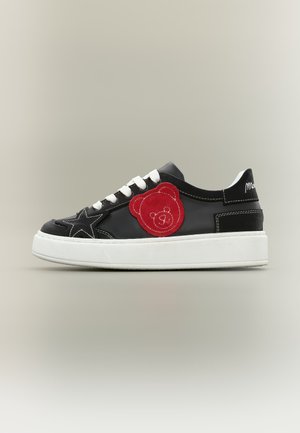 Basket noire avec semelle et lacets blancs, patch nounours rouge sur le côté, et étoile noire cousue près des orteils.
