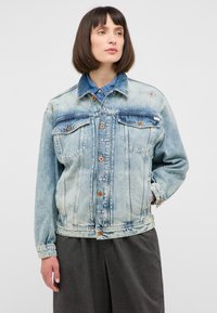 Jasnoniebieska kurtka dżinsowa z zapinaniem na guziki, dwoma kieszeniami na piersi i subtelnymi wyszywanymi akcentami. Luźny krój i długie rękawy.