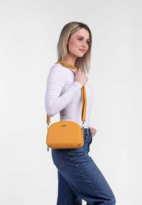 Yellow quilted crossbody bag with a rounded shape, textured surface, and adjustable strap, highlighted by silver hardware accents.