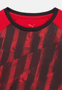 Κόκκινο και μαύρο κοντομάνικο πουκάμισο με στρογγυλή λαιμόκοψη. Διαθέτει υφασμένο γραφικό μοτίβο και μαύρη επένδυση γύρω από τη λαιμόκοψη.