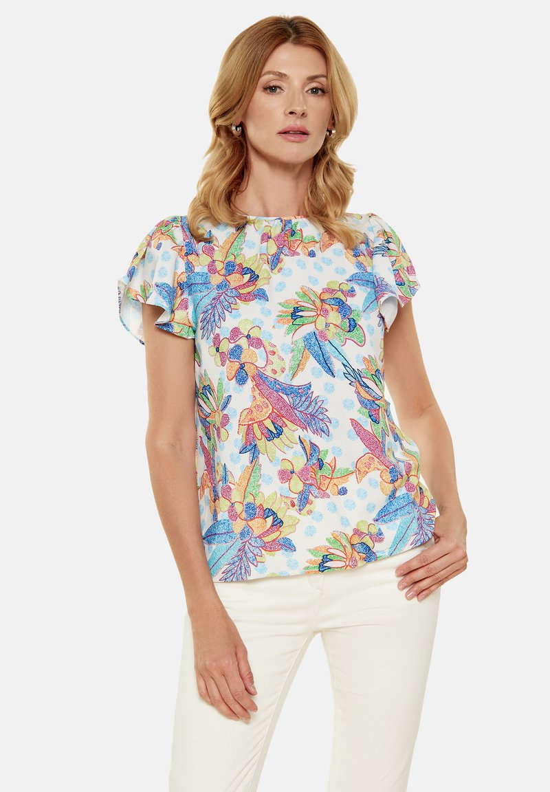 Top a maniche corte con un vivace motivo floreale e di uccelli in rosa, blu e verde su uno sfondo azzurro chiaro. Tessuto morbido con maniche arricciate.