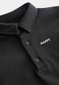 Czarny polo z kołnierzykiem, z dwiema czarnymi guzikami i białym haftowanym napisem "HAPPY" na klatce piersiowej. Teksturowany materiał o żeberkowym wykończeniu.