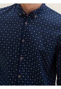 Camicia button-up blu navy con un piccolo motivo a croce bianco, colletto e bottoni marroni, realizzata in tessuto liscio con una leggera lucentezza.