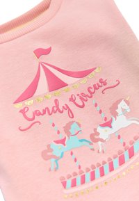 Sudadera rosa con un diseño de carrusel que incluye unicornios, acentos de purpurina y el texto "Candy Circus" en una escritura juguetona.
