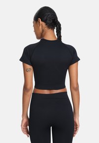 Czarny krótki top sportowy z krótkim rękawem, wykonany z gładkiego materiału. Charakteryzuje się dopasowanym krojem i okrągłym dekoltem.