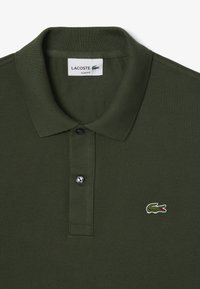 Polo shirt slim fit in verde oliva, con tessuto texturizzato, una patta con tre bottoni e un piccolo logo di coccodrillo ricamato.