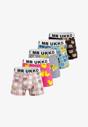 Shirtloze man met mullet en snor houdt zijn handen onder zijn kin, draagt beige geruite boxershorts met berengezichten en een "MR UKKO" tailleband.