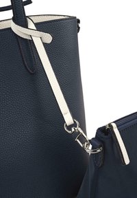 Bolso tote de cuero azul marino con acentos blancos, superficie texturizada y herrajes de plata; incluye un pequeño estuche con cremallera extraíble.