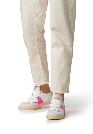 Witte sneakers met roze suède accenten, een gestructureerd oppervlak en een gevoerde zool. Gecombineerd met crème-kleurige, rechte jeans.