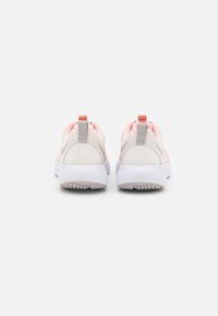 Baskets légères avec un dessus en mesh beige et rose, dotées d'une semelle blanche texturée et de languettes contrastées sur le talon.