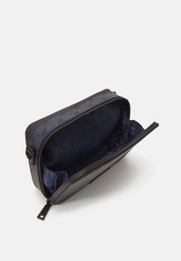 Marineblaue Tasche mit glattem, schwarzem Lederbesatz, Reißverschluss und gemustertem blauen Stoff. Innenfutter aus dunklem Satinmaterial.