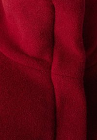 Tela de lana roja con una textura suave y fina, que presenta costuras limpias y contornos suaves. El material parece grueso y cálido.